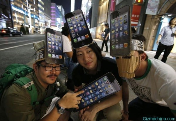 Men wearing cardboard hats, depicting Apple's new iPhone 5, pose for photos as they wait for the release of the phone near Apple Store Ginza in Tokyo