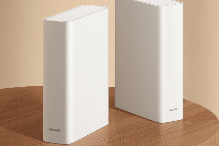 Two white Huawei Router X2 devices with a book-style design stand on a wooden table.