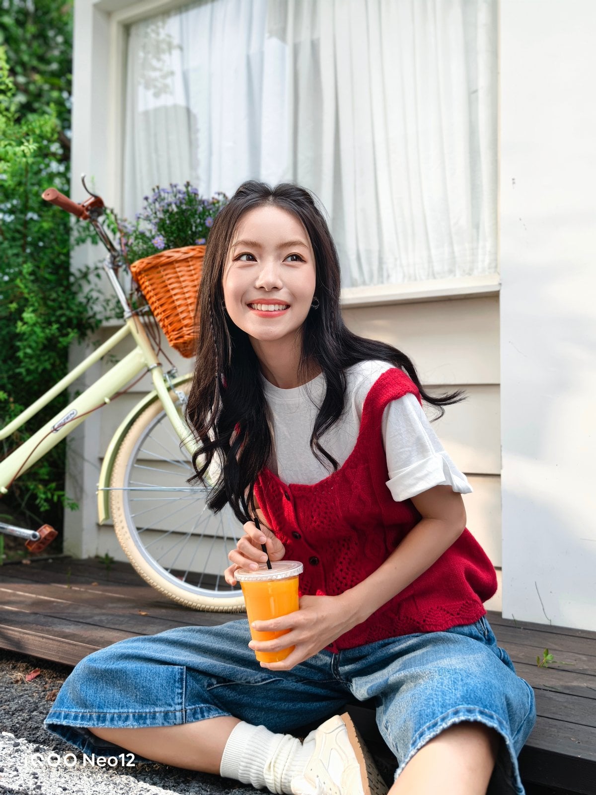 iQOO Neo 12 camera sample showing an outdoor portrait of a woman seated beside a bicycle