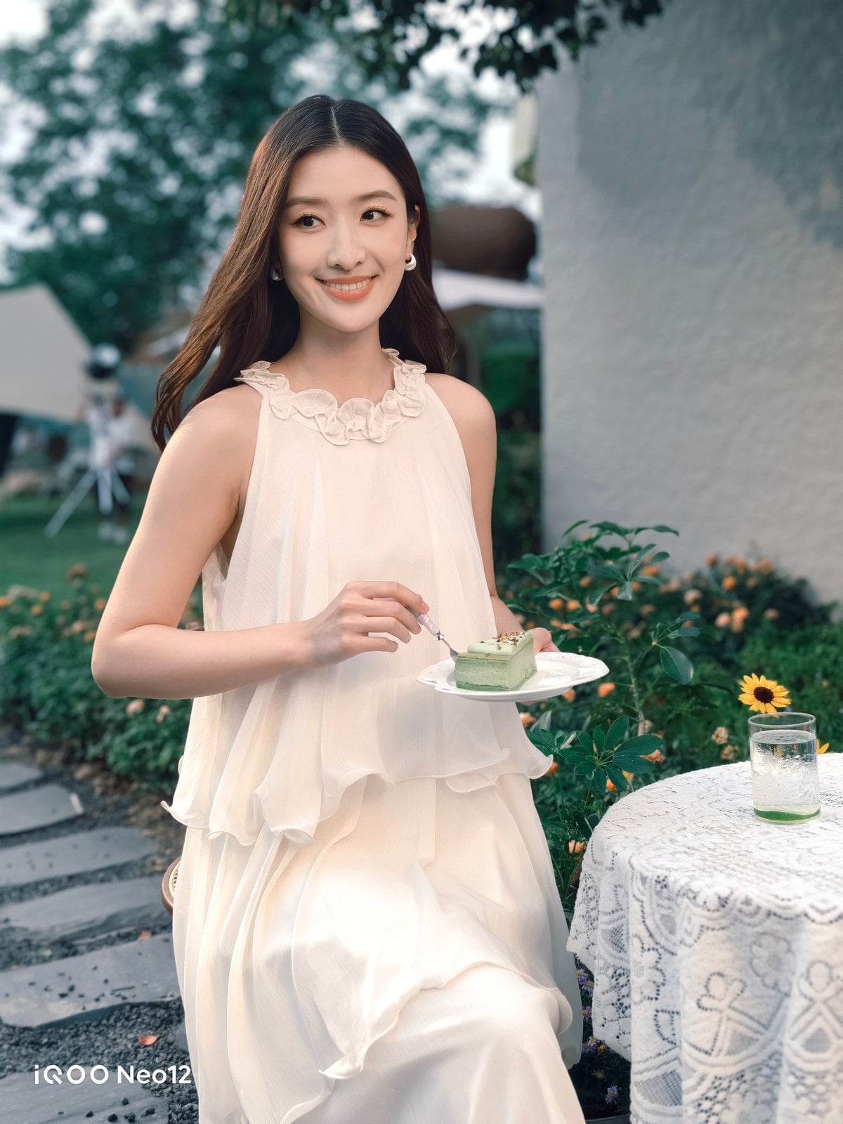iQOO Neo 12 camera sample showing a garden portrait of a woman in a white dress