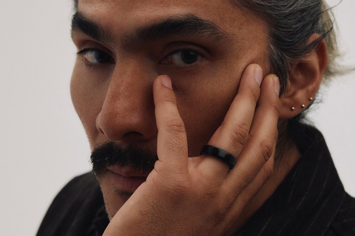 Man resting his hand against his face while wearing the Oura Ring 5 in the Black finish