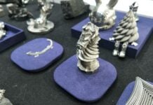 SnowX SnowPod on TCT Shenzhen: A Desktop Metal 3D Printer That Actually Fits on Your Desk Various metal 3D printed objects displayed on blue pads at a trade show booth.